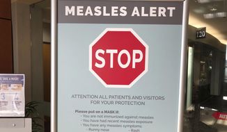 In this Jan. 30, 2019, file photo, a sign warning patients and visitors of a measles outbreak is shown posted at The Vancouver Clinic in Vancouver, Wash. (AP Photo/Gillian Flaccus, File) **FILE** 