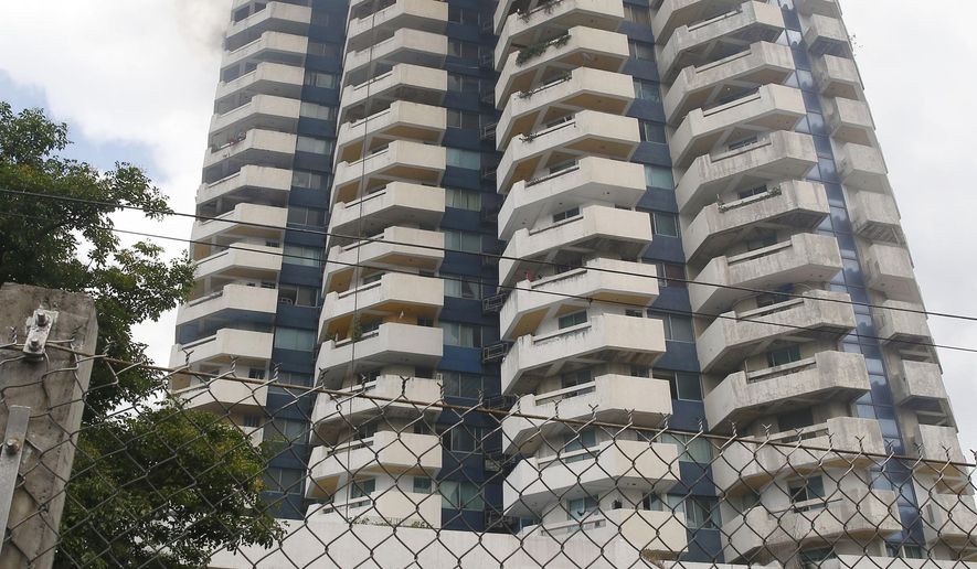 Firemen watch as a fire rages through the top floors of the 21-story Pacific Coastal Plaza condominium in suburban Paranaque, south of Manila, Philippines Monday, April 29, 2019. Officials say more than 100 firetrucks converged Monday to battle the blaze that hit residential building in the Paranaque city area of Manila, where one lane of a coastal road along Manila Bay was closed due to falling debris. (AP Photo/Bullit Marquez)