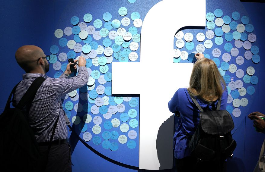 Attendees stick notes on a Facebook logo at F8, the Facebook&#39;s developer conference, Tuesday, April 30, 2019, in San Jose, Calif. (AP Photo/Tony Avelar )