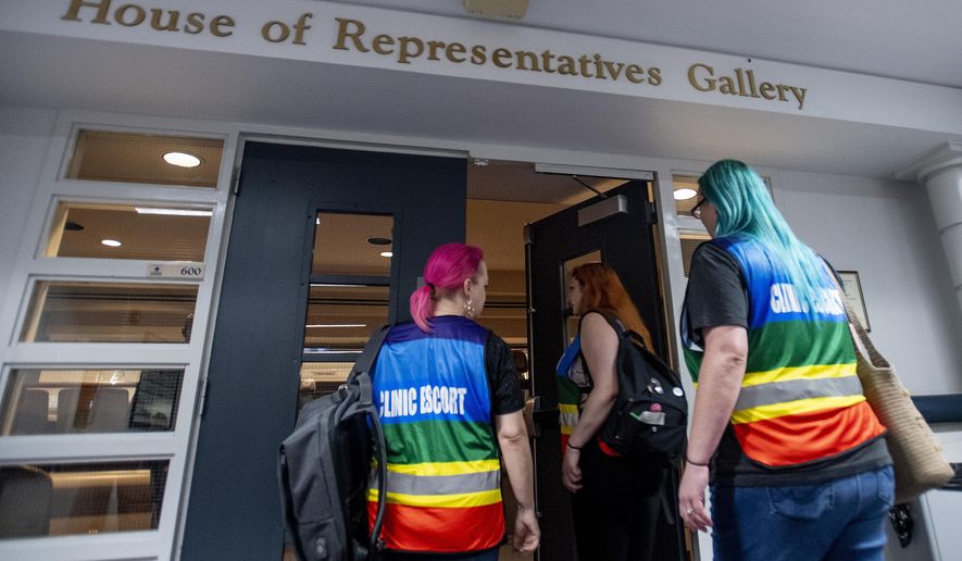 Women's heath clinic escorts, from left Mia Raven, Margeaux Hartline and Kari Crowe walk into the gallery to watch debate on the abortion ban bill at the Alabama Statehouse in Montgomery, Ala., on Tuesday April 30, 2019. The House of Representatives on Tuesday will debate the proposal to make performing an abortion a felony. The bill contains an exemption for the mother's health but not for rape or incest.The legislation is purposely designed to conflict with the 1973 Roe v. Wade Supreme Court decision legalizing abortion nationally. (Mickey Welsh/The Montgomery Advertiser via AP)