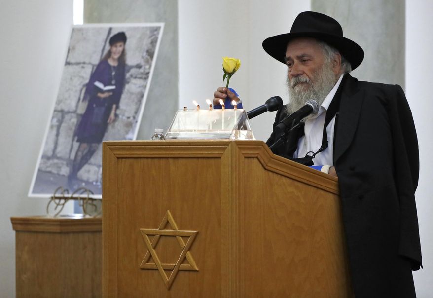 Yisroel Goldstein, rabbi of Chabad of Poway, holds a yellow rose as he speaks Monday, April 29, 2019, at the funeral for Lori Kaye, who is pictured at left, in Poway, Calif. Kaye, who was was killed Saturday when a gunman opened fire inside the Chabad of Poway synagogue, had given Goldstein the flower as part of a bouquet the day before the shooting, which also injured Goldstein. (AP Photo/Gregory Bull)