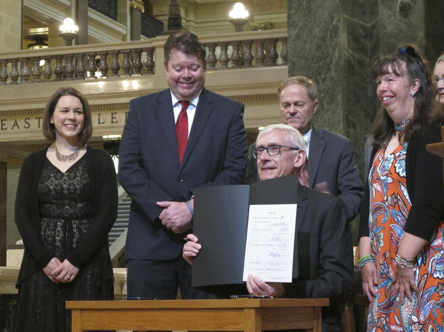Wisconsin Gov. Tony Evers, center, displays his first bill signed into law, Tuesday, April 30, 2019, a measure that removes the term "mental retardation" from state agency rules and regulations. Watching him sign from left to right are Kimber Liedl from Senate Majority Leader Scott Fitzgerald's office, Republican state Rep. John Jagler, Republican Sen. Rob Cowles and Yael Kerzan, an advocate for the bill who has Williams syndrome. (AP Photo/Scott Bauer)