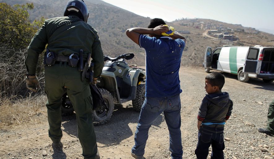 In this June 28, 2018, file photo, a Guatemalan father and son, who crossed the U.S.-Mexico border illegally, are apprehended by a U.S. Border Patrol agent in San Diego. California will introduce group trials on Monday, July 9, for people charged with entering the country illegally. Federal prosecutors in Arizona, Texas and New Mexico have long embraced these hearings, which critics call assembly-line justice. California was a lone holdout and the Justice Department didn&#x27;t seriously challenge its position until the arrival of Attorney General Jeff Sessions. (AP Photo/Jae C. Hong, File)