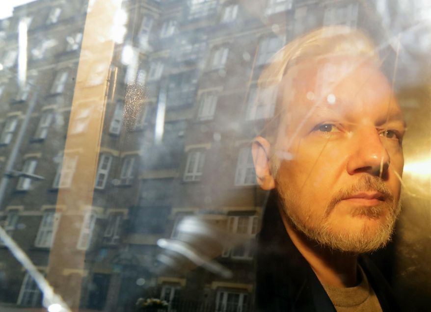 Buildings are reflected in the window as WikiLeaks founder Julian Assange is taken from court, where he appeared on charges of jumping British bail seven years ago, in London, Wednesday May 1, 2019. Assange has been jailed for 50 weeks for breaching his bail after going into hiding in the Ecuadorian embassy in London.(AP Photo/Matt Dunham)