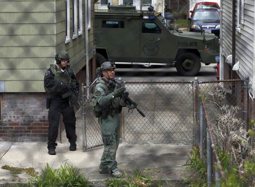 Police officers search a backyard in the Davis Square neighborhood after someone fired a weapon at officers responding to a bank robbery Wednesday, May 1, 2019, in Somerville, Mass. (AP Photo/Michael Dwyer)