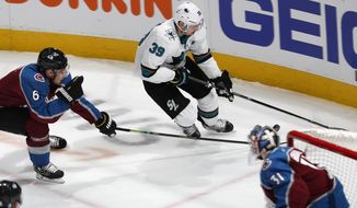 San Jose Sharks center Logan Couture, back right, drives to the net with the puck as Colorado Avalanche defenseman Erik Johnson, back left, and goaltender Philipp Grubauer defend during the first period of Game 3 of an NHL hockey second-round playoff series Tuesday, April 30, 2019, in Denver. (AP Photo/David Zalubowski)