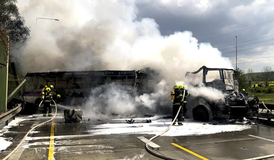 In this handout photo provided by Hasicsky Zachrany Sbor or HZS Praha, Czech Republic's firefighters put out remaining fire at the scene of a crash in Prague, Czech Republic, Thursday, May 2, 2019. Czech firefighters and police say a bus with prisoners caught fire after colliding with two trucks, one of them carrying two tanks. The Prague rescue service says one person has died in the crash that occurred on Thursday on a busy ring road that leads to Prague's international airport. (HZS Praha via AP)
