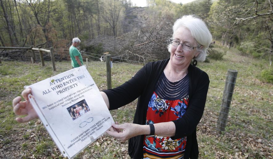 FILE - In this May 3, 2018, file photo, Becky Crabtree displays a flyer that she posted on a fence on the route of the proposed Mountain Valley pipeline on their property in Lindside, W.Va. A Virginia-based legal group is asking the U.S. Supreme Court to end what it says has become an abuse of eminent domain by companies that build natural-gas pipelines. (AP Photo/Steve Helber, File)