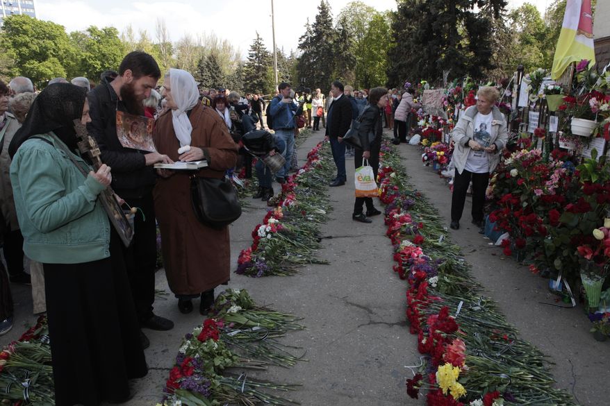 People lay flowers as they gather outside the burnt trade union building to commemorate the five-year anniversary of deadly clashes which killed dozens of demonstrators supporting Ukraine's government and pro-Russia protesters, in Odessa, Ukraine, Thursday, May 2, 2019. Five years after 48 people died in clashes in the Ukrainian city of Odessa, including dozens in a burning building, the UN human rights monitoring mission in the country is criticizing authorities for delays in prosecution and investigation of the violence. (AP Photo/Sergei Poliakov)