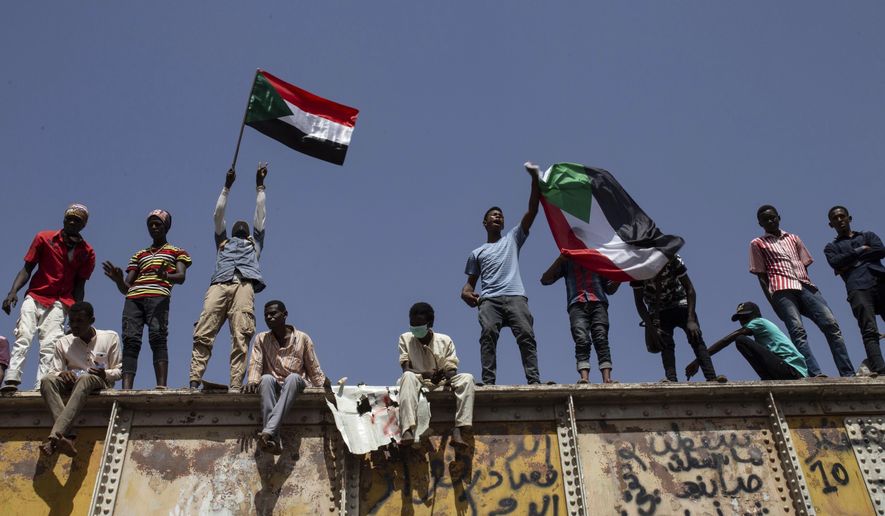 Sudanese protesters wave national flags at the sit-in outside the military headquarters, in Khartoum, Sudan, Thursday, May 2, 2019. Sudan's protesters are holding a mass rally to step up pressure on the military to hand power to civilians following last month's overthrow of President Omar al-Bashir. (AP Photos/Salih Basheer)
