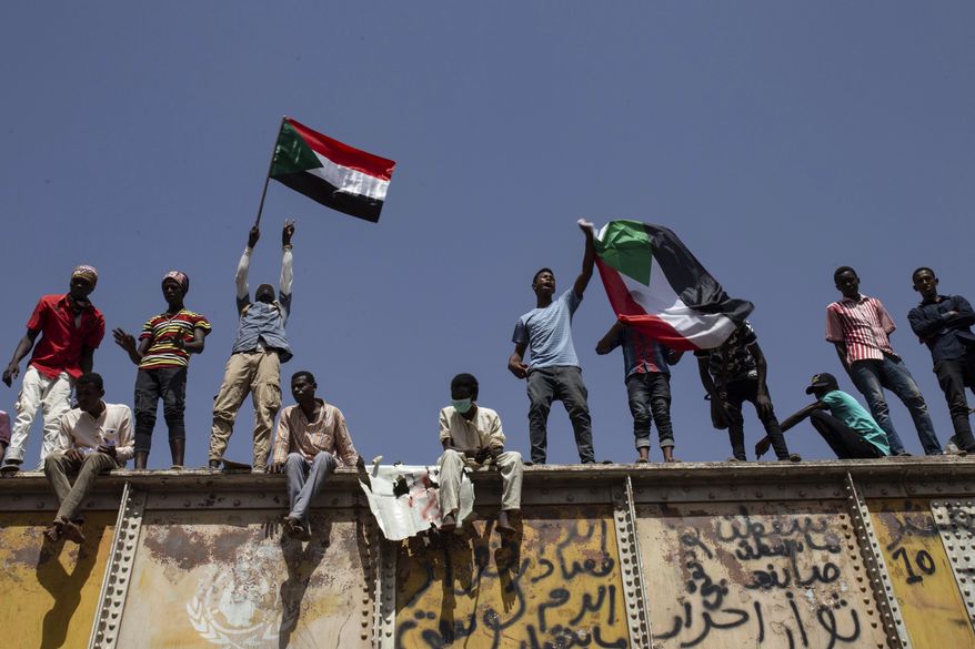Sudanese protesters wave national flags at the sit-in outside the military headquarters, in Khartoum, Sudan, Thursday, May 2, 2019. Sudan's protesters are holding a mass rally to step up pressure on the military to hand power to civilians following last month's overthrow of President Omar al-Bashir. (AP Photos/Salih Basheer)