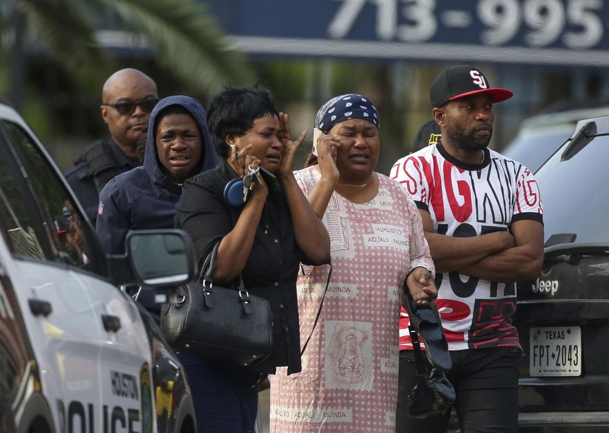 In this Thursday, May 2, 2019 photo, family members of Alberto Nduli, who was fatally struck by a vehicle, grieve as Houston Police investigate the scene in Houston. Authorities say a tow truck driver has been arrested and charged after Nduli died while trying to stop the driver from repossessing his SUV. (Godofredo A. Vásquez/Houston Chronicle via AP)