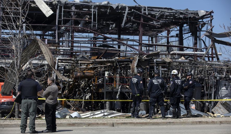 Debris can be seen as emergency personnel and others search and clear the scene of an explosion and fire at AB Specialty Silicones chemical plant Saturday, May 4, 2019, in Waukegan, Ill. An explosion and fire at an Illinois silicone factory was believed to have killed three people, authorities said Saturday, as they recovered the body of one victim while suspending the search for the other two. (Erin Hooley/Chicago Tribune via AP)