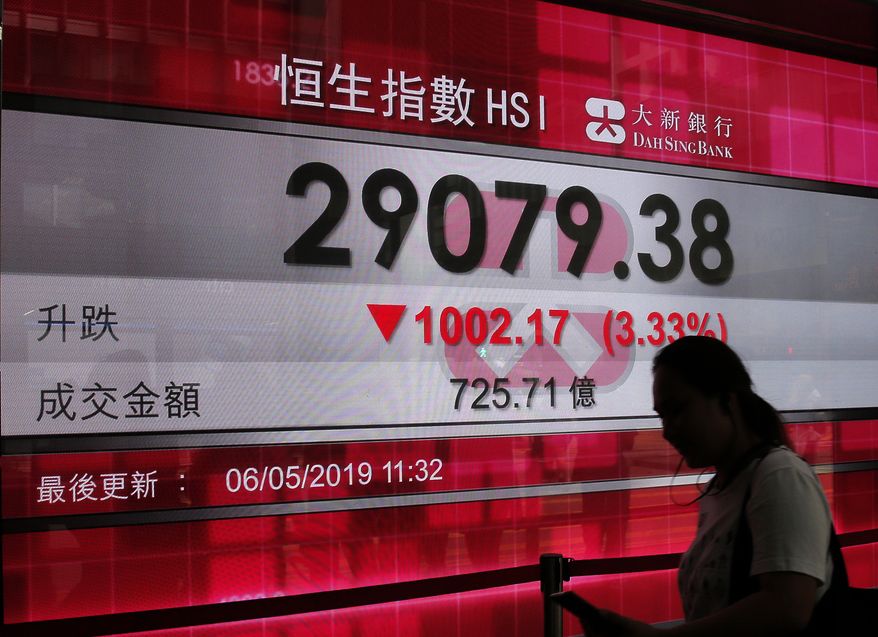 A woman walks past a bank's electronic board showing the Hong Kong share index at Hong Kong Stock Exchange Monday, May 6, 2019. Shares tumbled in Asia early Monday after President Donald Trump threatened in a tweet to impose more tariffs on China, spooking investors who had been expecting good news on trade. (AP Photo/Vincent Yu)