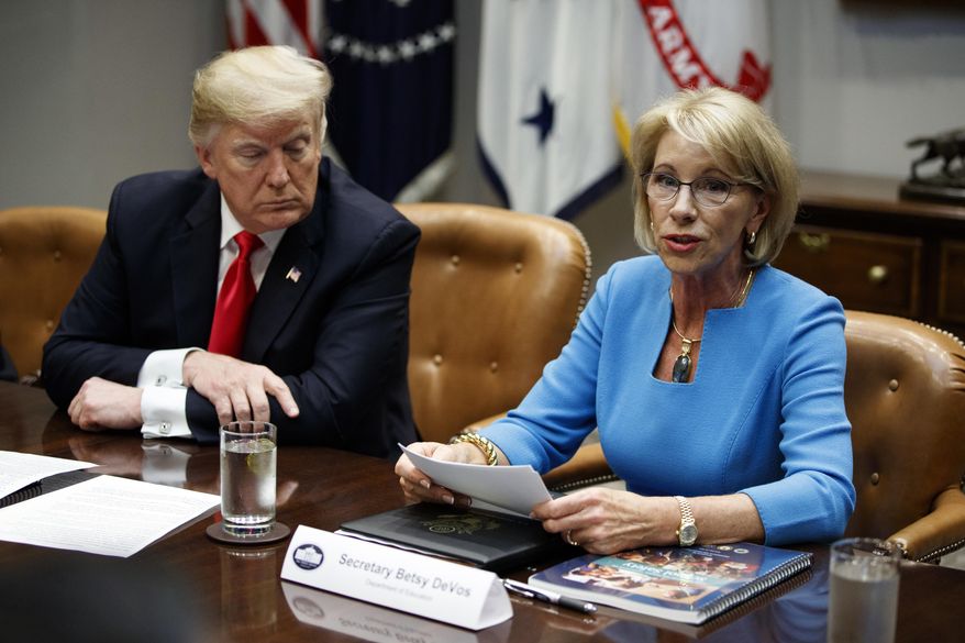 FILE - In this Dec. 18, 2018, file photo, President Donald Trump listens as Secretary of Education Betsy DeVos speaks during a roundtable discussion on the Federal Commission on School Safety report, in the Roosevelt Room of the White House in Washington. Education, it’s safe to say, is not Trump’s top priority. Instead, he entrusts that realm to DeVos, who after two years has emerged as one of the most polarizing figures in the Cabinet but also one of its most enduring members. (AP Photo/Evan Vucci, File)
