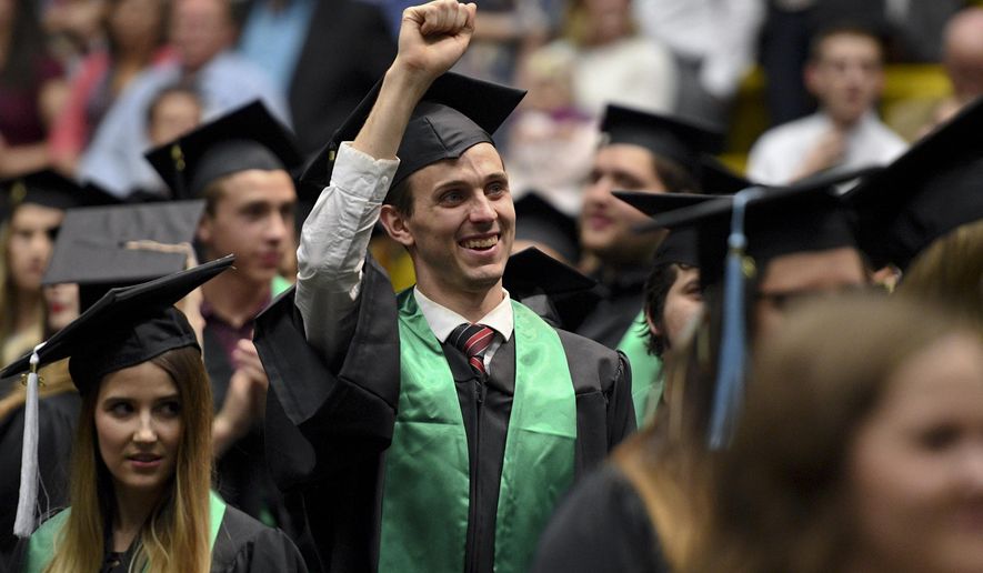 In this May 3, 2018, photo, T.J. Mullen, of West Jordan, graduates with an Associate degree in architectural drafting, waves to professors as they process in during Utah Valley University's 77th Commencement Ceremony, at the UCCU Center in Orem, Utah. Recycled graduation gowns worn by Utah Valley University graduates saved an estimated 70,000 plastic bottles from landfills this year, the Daily Herald reports. (Isaac Hale/Daily Herald, via AP)