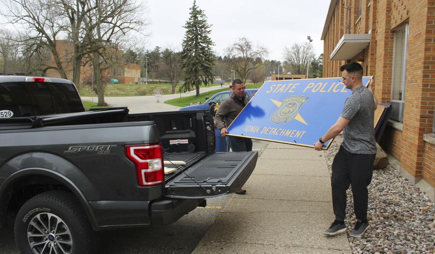 In this Tuesday, April 30, 2019 photo, Michigan State Police Lt. Christian Clute, left, and Trooper Colin Gensterblum carry an Ionia detachment sign from the old Riverside Correctional Facility to Clute's pickup truck during moving day. After operating out of an old Riverside Correctional Facility building for more than a decade, the Ionia detachment is relocating three miles north to the Ionia County Central Dispatch. (Elisabeth Waldon/The Daily News via AP)