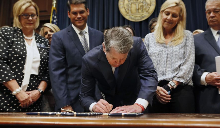 Georgia’s Republican Gov. Brian Kemp, center, signs legislation, Tuesday, May 7, 2019, in Atlanta, banning abortions once a fetal heartbeat can be detected, which can be as early as six weeks before many women know they’re pregnant. Kemp said he was signing the bill “to ensure that all Georgians have the opportunity to live, grow, learn and prosper in our great state.” (Bob Andres/Atlanta Journal-Constitution via AP)