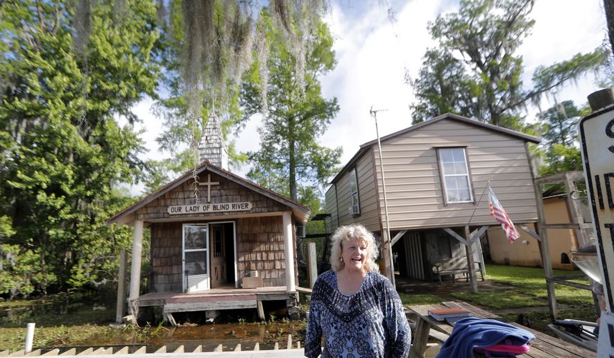 Pat Hymel stands on the dock in front of Our Lady of Blind River Chapel, along Blind River in St. James Parish, La., Tuesday, April 9, 2019. The chapel was built decades ago by her parents, Martha Deroche and her husband Bobby, after Martha had a vision of Jesus kneeling by a rock. Over the years, people have stopped by in boats or kayaks to pray in the one-room chapel. But floods over the years have damaged the little church, and the couple's grandson Lance Weber had to close it about two years ago out of safety concerns. (AP Photo/Gerald Herbert)