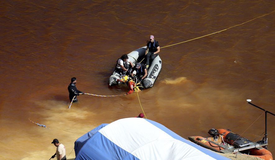 A diver walks out from a toxic man-made lake after his dive search for a third suitcase near the village of Mitsero outside of the capital Nicosia, Cyprus, Monday, May 6, 2019. Cyprus police spokesman Andreas Angelides said yesterday, investigators hunting for bodies dumped by a suspected serial killer pulled a suitcase containing decomposing human remains from a toxic lake. (AP Photo/Petros Karadjias)