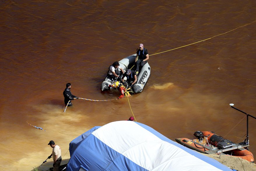 A diver walks out from a toxic man-made lake after his dive search for a third suitcase near the village of Mitsero outside of the capital Nicosia, Cyprus, Monday, May 6, 2019. Cyprus police spokesman Andreas Angelides said yesterday, investigators hunting for bodies dumped by a suspected serial killer pulled a suitcase containing decomposing human remains from a toxic lake. (AP Photo/Petros Karadjias)