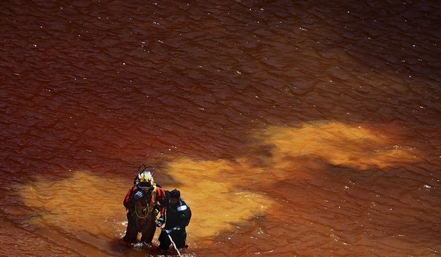 A diver takes a help from his colleague after a dive in a toxic man-made lake during a search for a third suitcase near the village of Mitsero outside of the capital Nicosia, Cyprus, Tuesday, May 7, 2019. New police chief Kypros Michailides has apologized to the families of seven foreign women and girls who an army captain has confessed to killing. (AP Photo/Petros Karadjias)