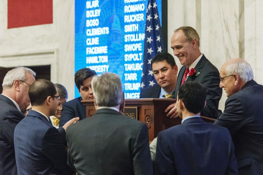 FILE - In this Feb. 18, 2019 file photo Senate President Mitch Carmichael, R-Jackson, speaks with other senators to work out a parliamentary question during debate in the state Senate chamber to amend an amended version of Senate Bill 451 passed by the House of Delegates at the West Virginia state Capitol in Charleston, W.Va. Carmichael has said he wants comprehensive education changes to improve classroom performances. The state Department of Education released a report Tuesday, May 7, 2019, that questioned the formation of charter schools and scoffed at education savings accounts as a way for parents to pay for students to attend them. (Craig Hudson/Charleston Gazette-Mail via AP, file)
