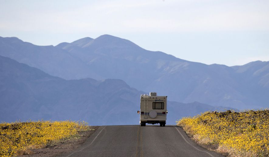 FILE - In this Feb. 24, 2016, file photo, wildflowers bloom as an RV travels along the road near Badwater Basin in Death Valley, Calif. Heading out on a road trip in a recreational vehicle allows travelers a unique opportunity to explore the nation while enjoying some comforts, too. (AP Photo/Jae C. Hong, File)