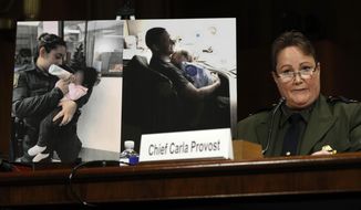 U.S. Border Patrol Chief Carla Provost testifies by a photo of agents with children during a Senate Judiciary Border Security and Immigration Subcommittee hearing about the border, Wednesday May 8, 2019, on Capitol Hill in Washington. (AP Photo/Jacquelyn Martin)