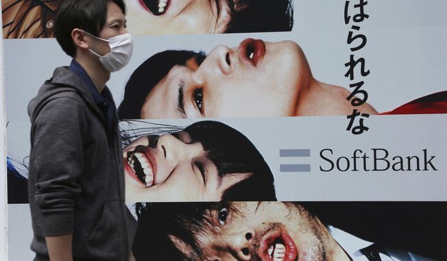In this April 15, 2019, photo, a man walks past an advertisement of Japanese telecoms company Softbank Corp. at its mobile phone shop in Tokyo. Softbank said Wednesday, May 8, 209, it will spend 456.5 billion yen ($4 billion) to increase its stake in Yahoo Japan to nearly 45%. The company forecast that with the additional stake in Yahoo, its revenue will rise to 4.8 trillion yen ($43.6 billion) in this fiscal year. (AP Photo/Koji Sasahara)