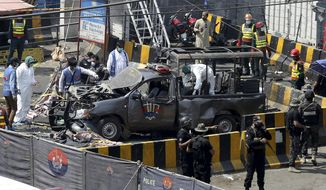 Pakistani security personnel surround a damaged police van in Lahore, Pakistan, Wednesday, May 8, 2019. A powerful bomb exploded near security forces guarding a famous Sufi shrine in Pakistan on Wednesday, police said. (AP Photo/K.M. Chaudary)