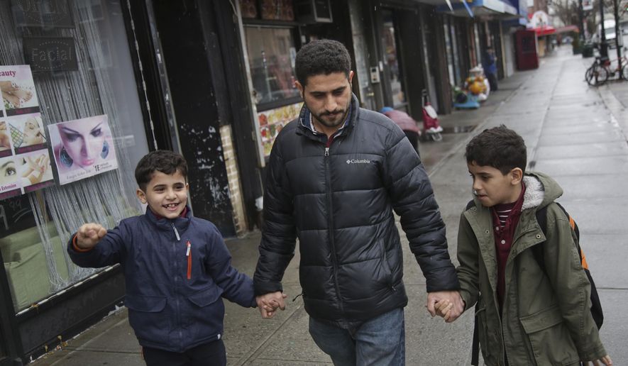 In this March 21, 2019, photo, Sadek Ahmed walks with his sons Adel, 9, right, and Mutaz, 7, after picking them up from school in the Brooklyn borough of New York. Their mother, Amena Abdulkarem, is stuck in Yemen with her two younger sons, the boys’ brothers. Their family’s situation is representative of the toll that the Trump administration’s almost-forgotten travel ban has taken on an untold number of families. (AP Photo/Seth Wenig)