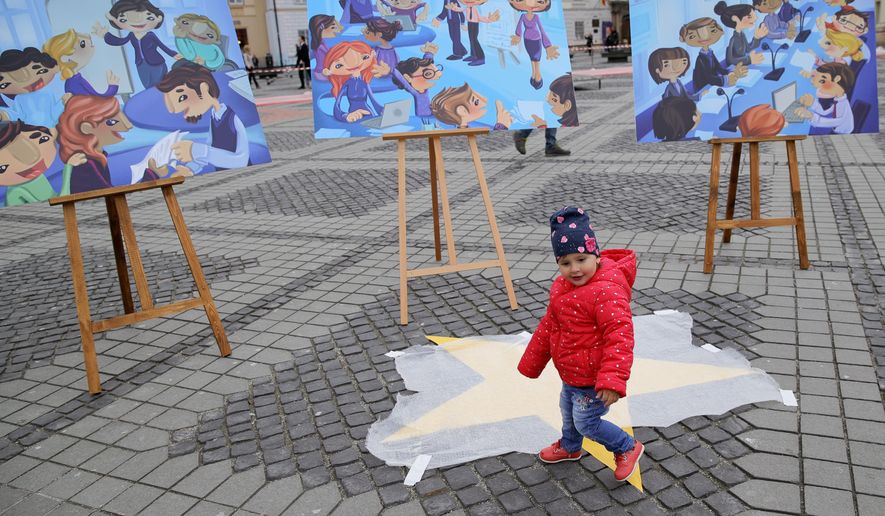 A child walks by boards depicting the creation of the Bucharest EU Children Declaration, a call for EU leaders to make child participation a priority, by children supported by UNICEF in the Piata Mare square in the Transylvanian town of Sibiu, Romania, Wednesday, May 8, 2019. European Union leaders hold an EU summit in Sibiu on Thursday to start setting out a course for increased political cooperation in the wake of the impending departure of the United Kingdom from the bloc. (AP Photo/Vadim Ghirda)