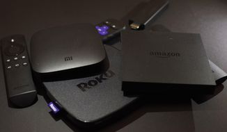 This Nov. 16, 2016, photo shows Xiaomi&#39;s Mi Box, left, the Roku Premiere, center, and the Amazon Fire TV streaming TV devices in New York. (AP Photo, File)