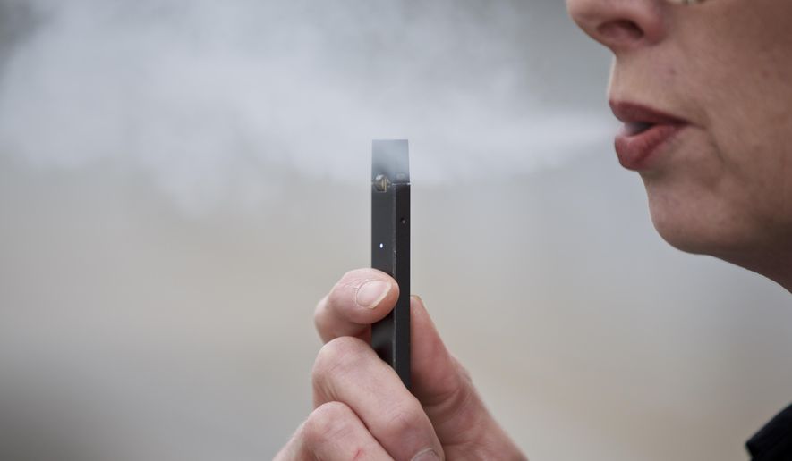 FILE - In this April 16, 2019, file photo, a woman exhales a puff of vapor from a Juul pen in Vancouver, Wash. Under intense scrutiny amid a wave of underage vaping, Juul is pushing into television with a multimillion-dollar campaign rebranding itself as a stop-smoking aid for adults trying to kick cigarettes. (AP Photo/Craig Mitchelldyer, File)