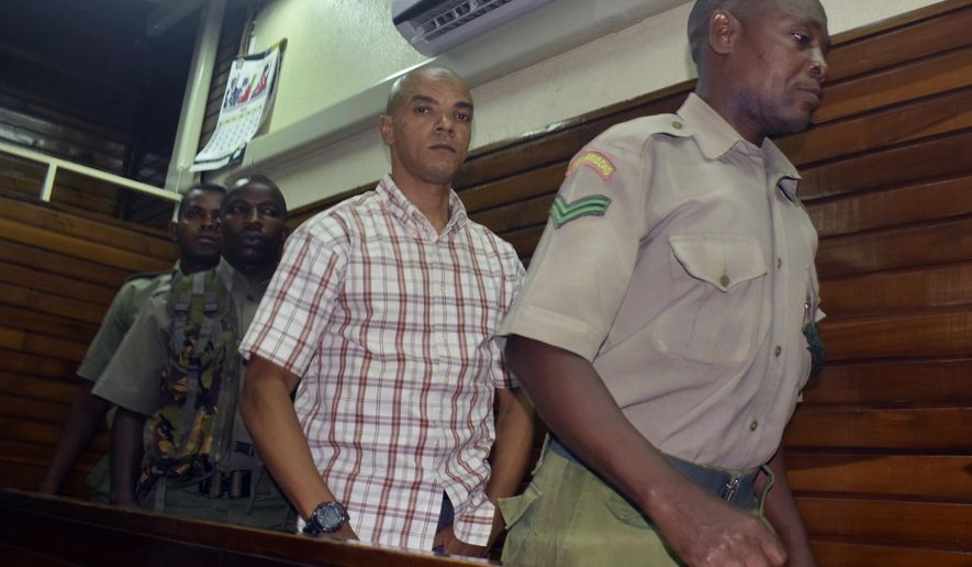 Guarded by heavy security, British suspect Jermaine Grant, centre, walks out of a Mombasa court after being sentenced, in Mombasa, Kenya, Thursday, May 9, 2019, A Kenyan court has jailed a British national believed to be part of an extremist cell to four years in prison for possession of bomb making material. (AP Photo)