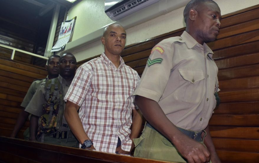 Guarded by heavy security, British suspect Jermaine Grant, centre, walks out of a Mombasa court after being sentenced, in Mombasa, Kenya, Thursday, May 9, 2019, A Kenyan court has jailed a British national believed to be part of an extremist cell to four years in prison for possession of bomb making material. (AP Photo)