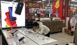 A man browses an iPhone unit on display at a section selling Apple&#39;s products together with Chinese made electric appliances at a hypermarket in Beijing, Thursday, May 9, 2019. Ratcheting up tension ahead of talks in Washington, China vowed Thursday to defend its own interests and retaliate if President Donald Trump goes ahead with more tariff hikes in a dispute over trade and technology. (AP Photo/Andy Wong)