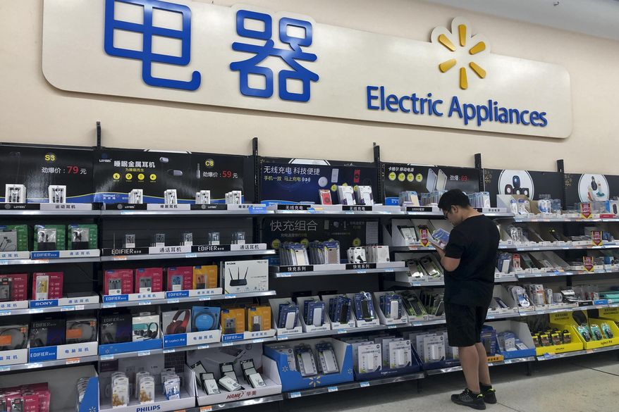 A man looks at power banks at a section selling digital accessories at a hypermarket in Beijing, Thursday, May 9, 2019. Ratcheting up tension ahead of talks in Washington, China vowed Thursday to defend its own interests and retaliate if President Donald Trump goes ahead with more tariff hikes in a dispute over trade and technology. (AP Photo/Andy Wong)