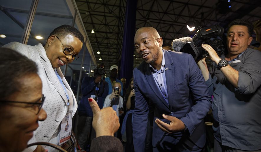 Mmusi Maimane, leader of the largest opposition party, the Democratic Alliance, is greeted by a supporter as he visits the Independent Electoral Commission Results Center in Pretoria, South Africa Thursday, May 9, 2019. South Africans voted Wednesday in a national election and preliminary results show that the ruling African National Congress party (ANC) has an early lead in the national elections but has seen its share of the vote drop significantly. (AP Photo/Ben Curtis)