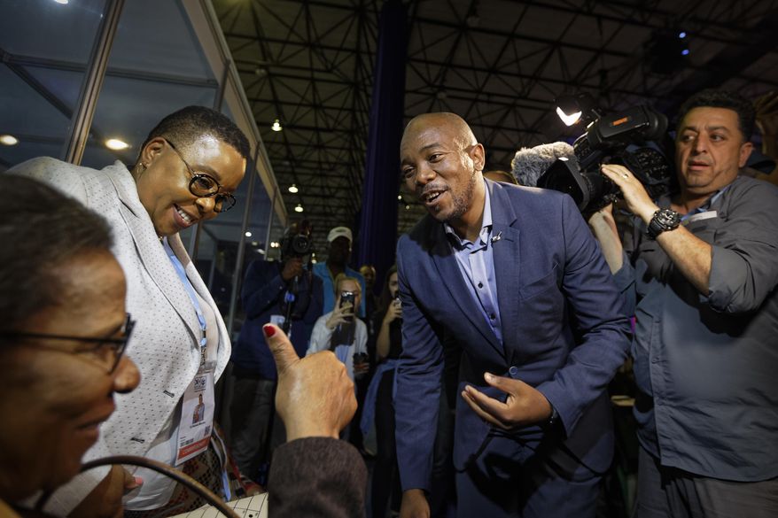 Mmusi Maimane, leader of the largest opposition party, the Democratic Alliance, is greeted by a supporter as he visits the Independent Electoral Commission Results Center in Pretoria, South Africa Thursday, May 9, 2019. South Africans voted Wednesday in a national election and preliminary results show that the ruling African National Congress party (ANC) has an early lead in the national elections but has seen its share of the vote drop significantly. (AP Photo/Ben Curtis)
