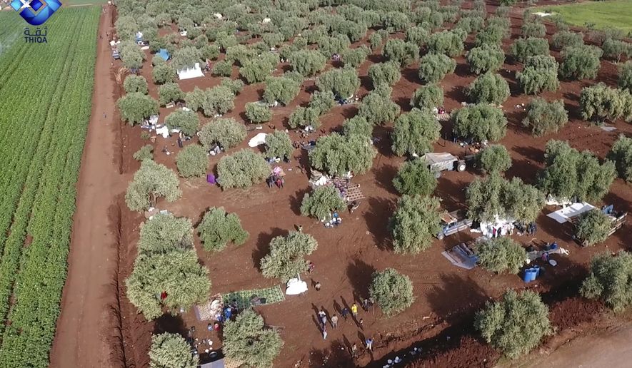 This frame grab from video provided by the activist-operated Thiqa News Agency, shows residents displaced from the latest violence that hit the last rebel stronghold, taking refuge in olives orchids near the town of al-Atmeh, in northern Idlib, Syria, Thursday, May 9, 2019. Syrian government troops captured the village of Qalaat al-Madiq, a northwestern village known for its medieval fortress, on Thursday as they move deeper toward Idlib province, the last major rebel stronghold, activists and pro-government media said. (Thiqa News Agency via AP)