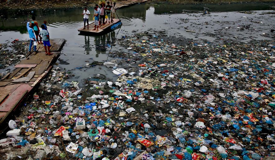 FILE - In this Sunday, Oct. 2, 2016 file photo, a man guides a raft through a polluted canal littered with plastic bags and other garbage in Mumbai, India. United Nations officials say nearly all of the world&#39;s countries have agreed on a deal to better manage plastic waste, with the United States a notable exception. A &amp;quot;legally binding framework&amp;quot; that affects thousands of types of plastic waste emerged Friday, May 10, 2019 after a two-week meeting of U.N.-backed conventions on plastic waste and toxic chemicals. (AP Photo/Rafiq Maqbool, file)