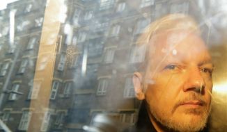 In this Wednesday, May 1, 2019, file photo, buildings are reflected in the window as WikiLeaks founder Julian Assange is taken from court, where he appeared on charges of jumping British bail seven years ago, in London. (AP Photo/Matt Dunham)