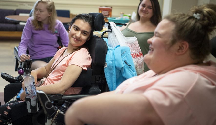 Veronica Siaba, of Queens, N.Y., center left, talks with Samantha Johnson, of New Jersey, Friday, May 3, 2019, in Rose Hall at Edinboro University in Edinboro, Pa.. Edinboro University has eliminated its attendent care program for students with disabilities. Neither student will be returning to the university after the summer. (Alexandra Wimley/Pittsburgh Post-Gazette via AP)/Pittsburgh Post-Gazette via AP)