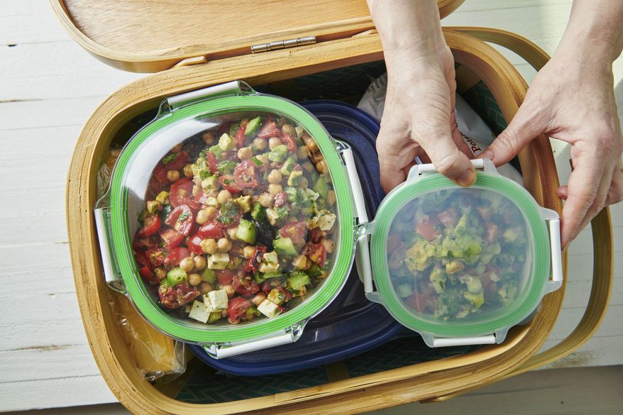 This May 2019 photo shows containers being packed in a picnic basket in New York. Whether it's a simple al fresco lunch or a romantic repast for two, a successful picnic takes planning. Make a checklist and gather ideas for which foods work best. (Cheyenne Cohen/Katie Workman via AP)