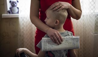 In this photo taken on Monday, March 11, 2019, Natalya Konkova holds her son, Yaroslav, during an interview with The Associated Press in Moscow, Russia. Konkova&#39;s son was one of nearly 130 Moscow children who were diagnosed with dysentery after eating food at one of the state-run day care centers and kindergartens in Moscow in December. (AP Photo/Alexander Zemlianichenko)