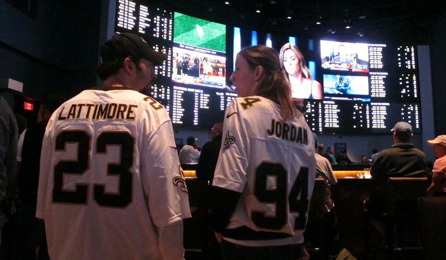 In this Sept. 9, 2018 photo, football fans wait for kickoff in the sports betting lounge at the Ocean Casino Resort in Atlantic City, N.J. Since sports betting became legal last year in New Jersey, the state's casinos and racetracks had taken more than $2.6 billion worth of bets through the end of April 2019. (AP Photo/Wayne Parry)