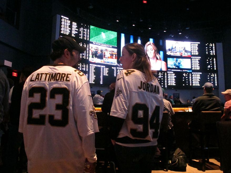 In this Sept. 9, 2018 photo, football fans wait for kickoff in the sports betting lounge at the Ocean Casino Resort in Atlantic City, N.J. Since sports betting became legal last year in New Jersey, the state's casinos and racetracks had taken more than $2.6 billion worth of bets through the end of April 2019. (AP Photo/Wayne Parry)