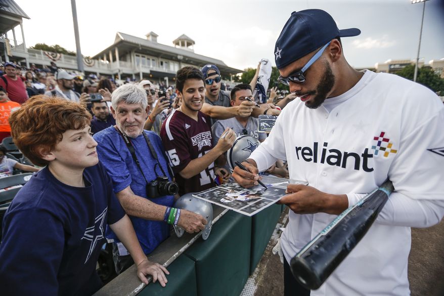 IMAGE DISTRIBUTED FOR RELIANT - Dak Prescott of the Dallas Cowboys signs memorabilia for fans during the eighth annual Reliant Home Run Derby Wednesday, May 15, 2019 in Frisco, Texas. Prescott, nine other Cowboys teammates and head coach Jason Garrett participated in the event, which helped raise a total of $100,100 on behalf of Reliant for local charities. (Brandon Wade/AP Images for Reliant)